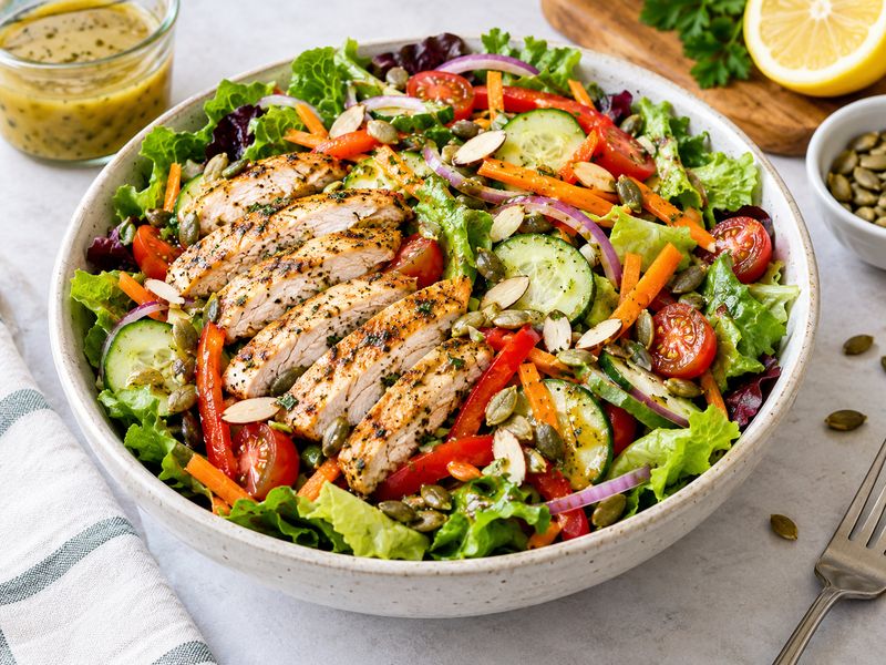 Grilled chicken garden salad with lettuce, tomatoes, cucumber, carrots, and lemon dressing