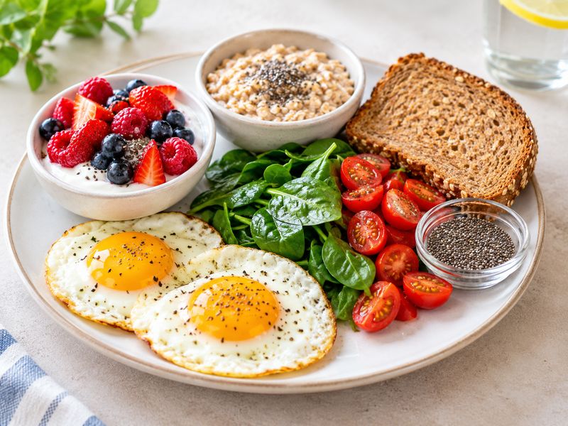 Healthy foods for a low calorie breakfast including eggs yogurt oats berries and toast