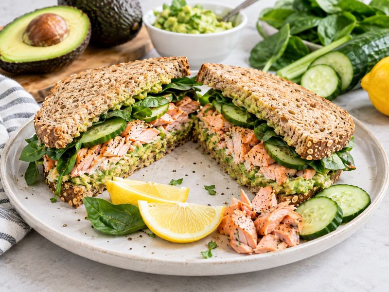 salmon avocado sandwich with cucumber spinach and lemon on whole grain bread