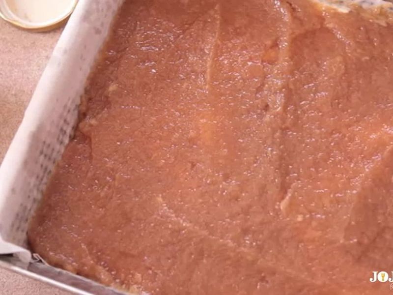 Applesauce cake batter evenly spread in a prepared 8-inch square baking pan