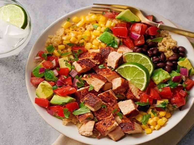 Chipotle chicken rice bowl with black beans, corn, avocado, tomatoes, and cilantro