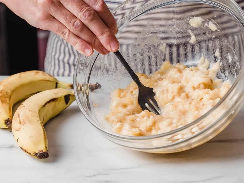 Ripe bananas mashed in a glass mixing bowl