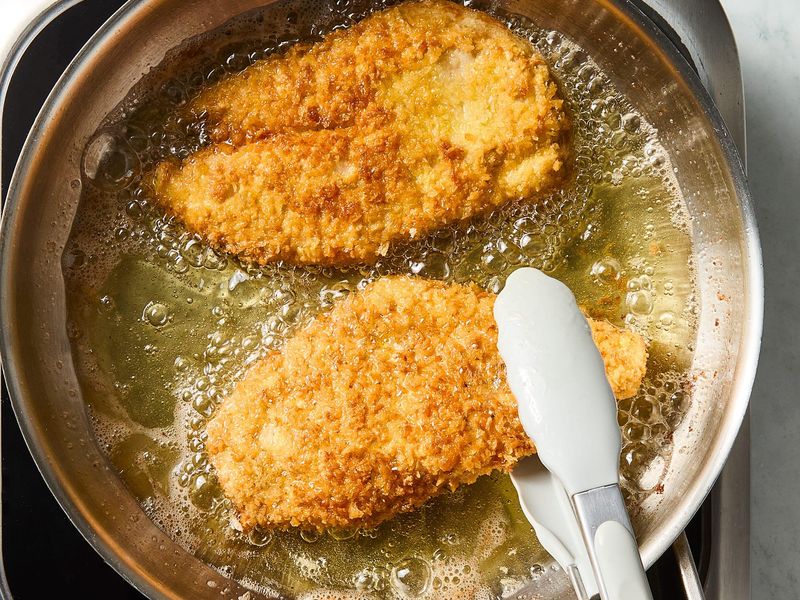 Breaded chicken cutlets frying in a skillet until golden and crispy