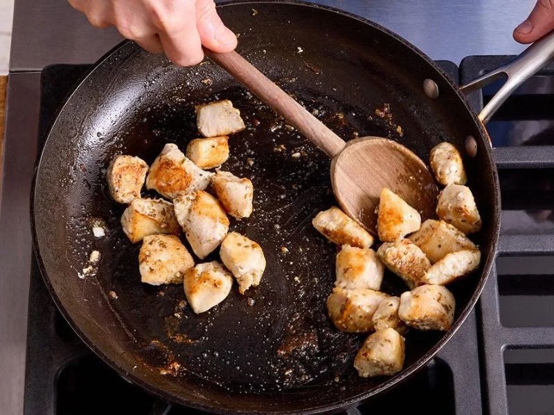 Chicken pieces browning in olive oil in a large skillet
