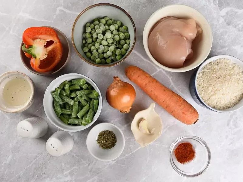 Ingredients for one pan chicken and rice including chicken, rice, broth, garlic, and vegetables