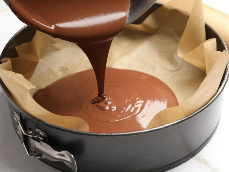 Chocolate cake batter spread evenly in a prepared round baking pan