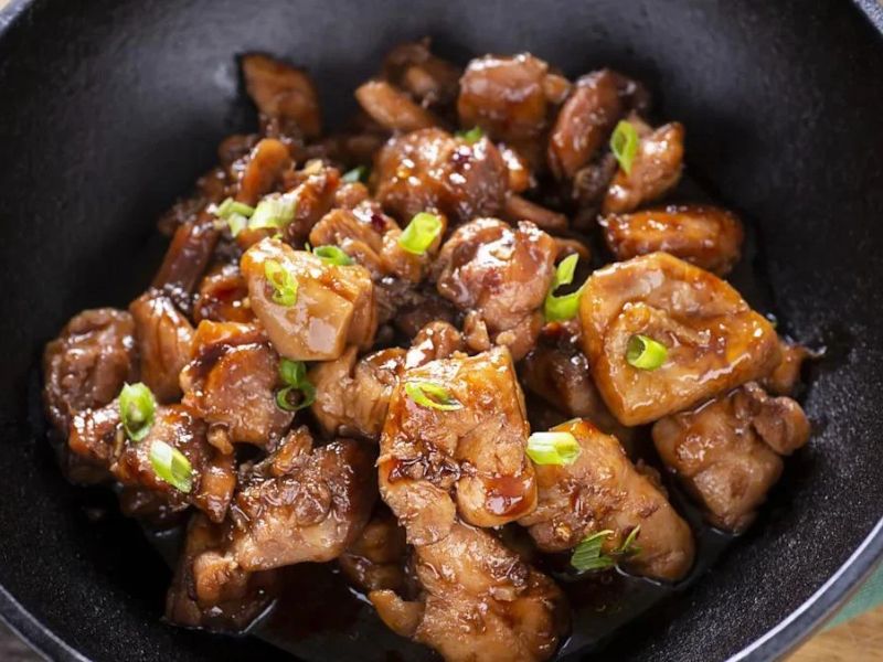 Thick glossy bourbon chicken sauce coating cooked chicken pieces