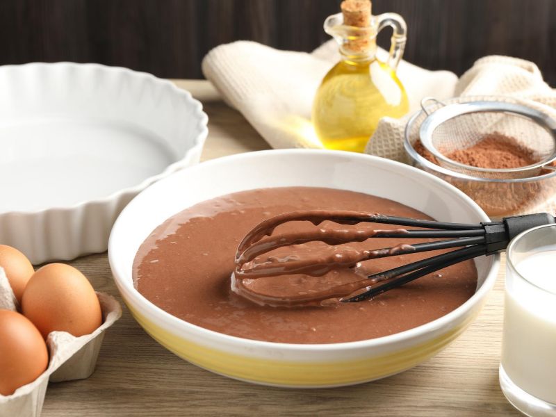 Smooth chocolate cake batter mixed in a glass bowl before baking