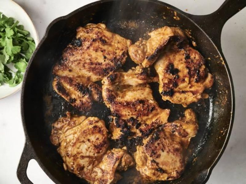 Chipotle chicken thighs browning in a skillet with a smoky seasoned crust