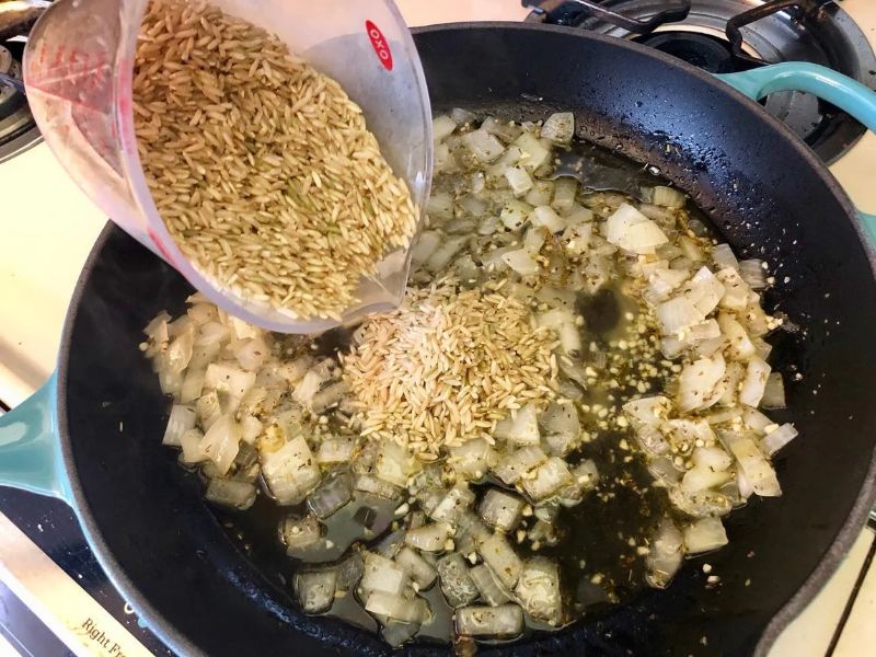 Long grain rice toasting with onion and garlic in a skillet