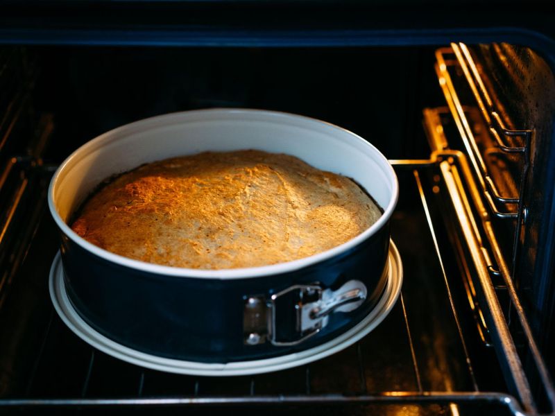 Banana cake baking in a round pan inside a preheated oven
