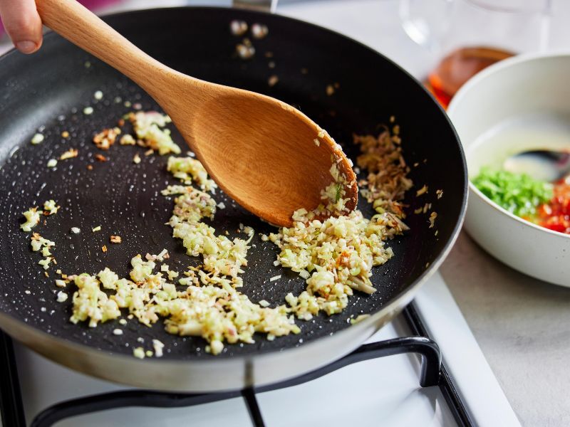 Minced garlic and grated ginger cooking in a skillet for bourbon chicken