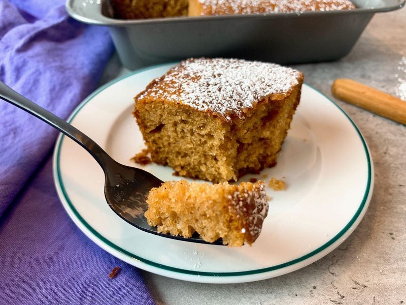 Moist homemade applesauce cake slice served on a plate with cinnamon for dessert