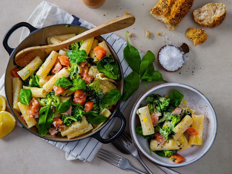Cooked pasta with salmon and vegetables in glass food storage containers