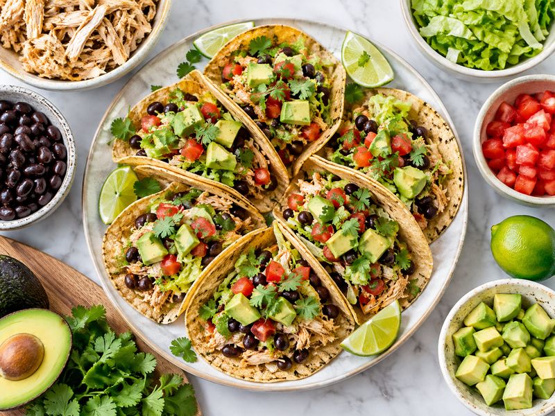 Healthy rotisserie chicken and black bean tacos with lettuce tomato avocado and lime