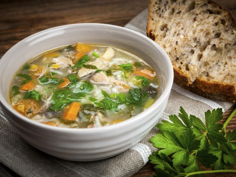 Homemade chicken vegetable soup served with whole-grain bread and salad